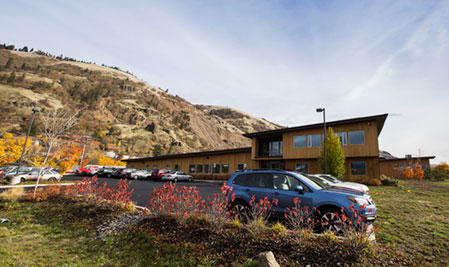 Cars parked beside a building in front of a mountain